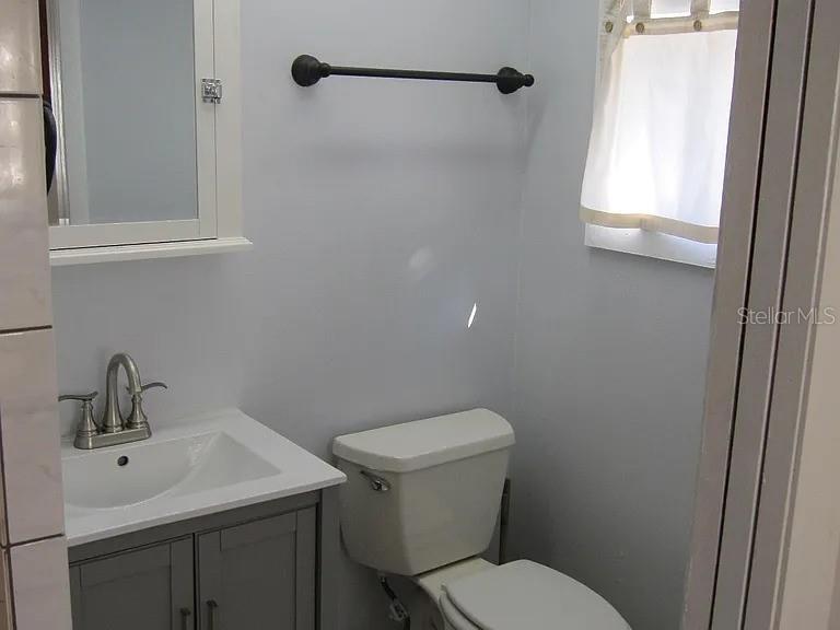 A small bathroom features a gray vanity, a white toilet, and a black towel bar — 28 N GROSSE AVENUE UNIT C, TARPON SPRINGS, FL