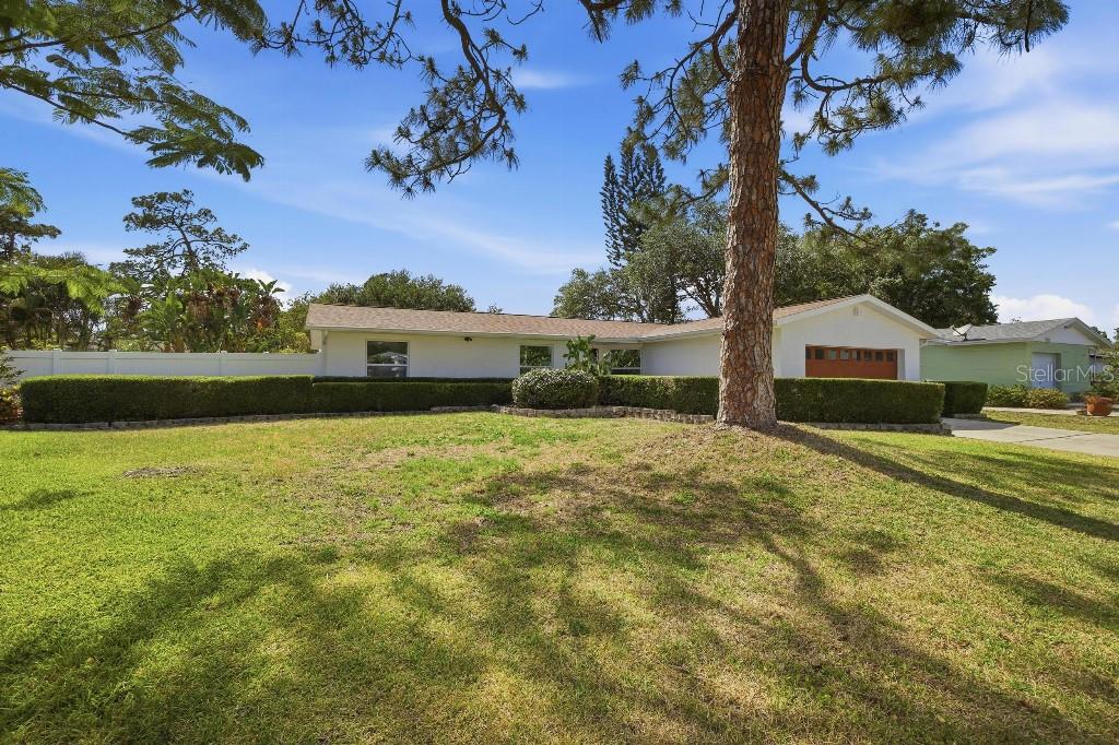 A single-story white house with a garage and a manicured hedge sits on a lawn — 7520 20TH STREET N, ST PETERSBURG, FL