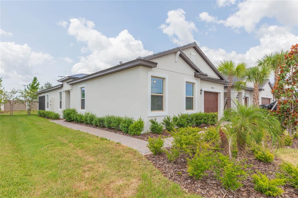 A single-story house with a light-colored stucco exterior, a brown roof, and a paved walkway — 10806 GABLE DIG LOOP, SAN ANTONIO, FL