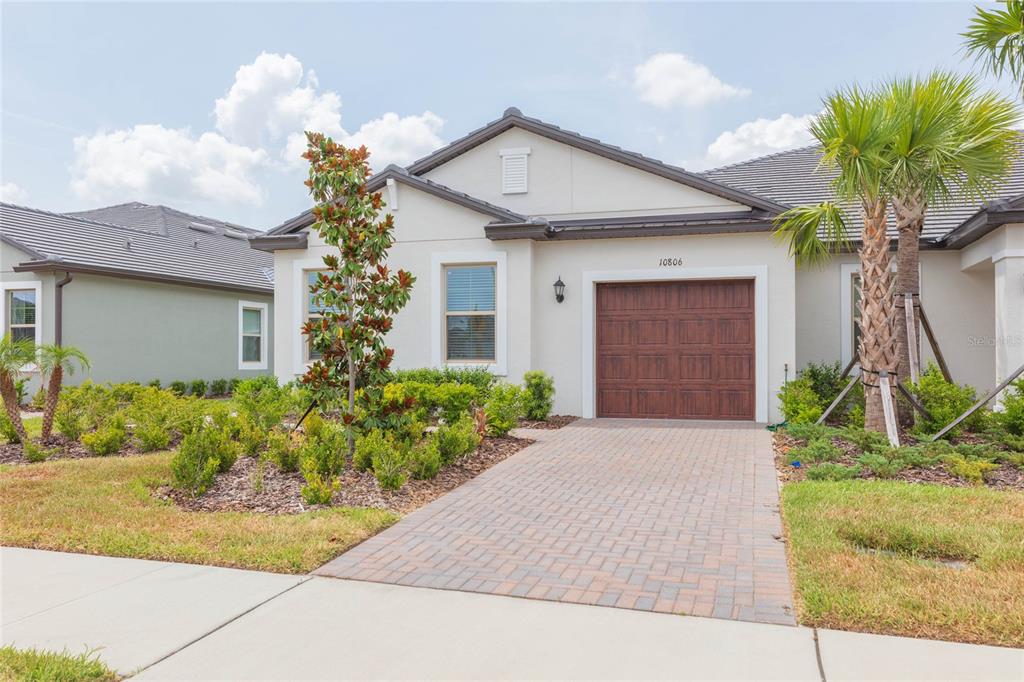 A single-story house with a paved driveway, a brown garage door, and landscaped front yard — 10806 GABLE DIG LOOP, SAN ANTONIO, FL