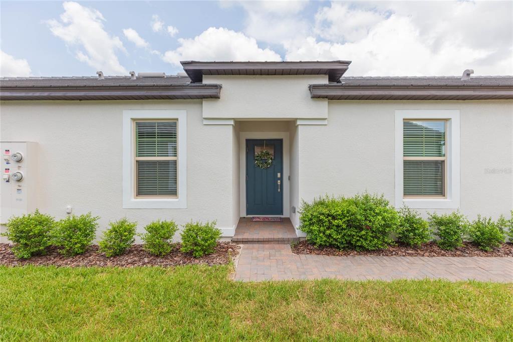 The exterior of a one-story home features a blue front door and two windows — 10806 GABLE DIG LOOP, SAN ANTONIO, FL