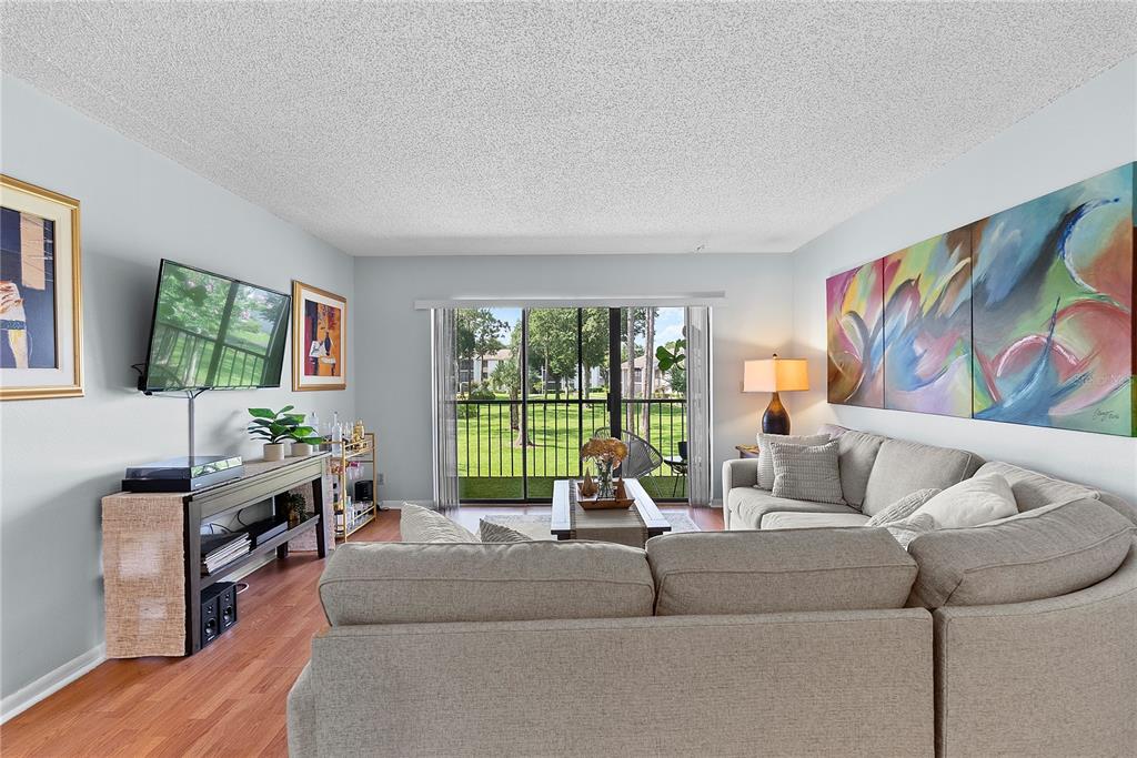 A living room features a large sectional sofa, a television on a console, and sliding doors — 8217 SUN SPRING CIRCLE UNIT 72, ORLANDO, FL