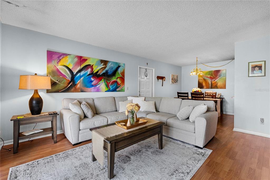 A living room features a gray sectional sofa, a coffee table, and colorful wall art — 8217 SUN SPRING CIRCLE UNIT 72, ORLANDO, FL