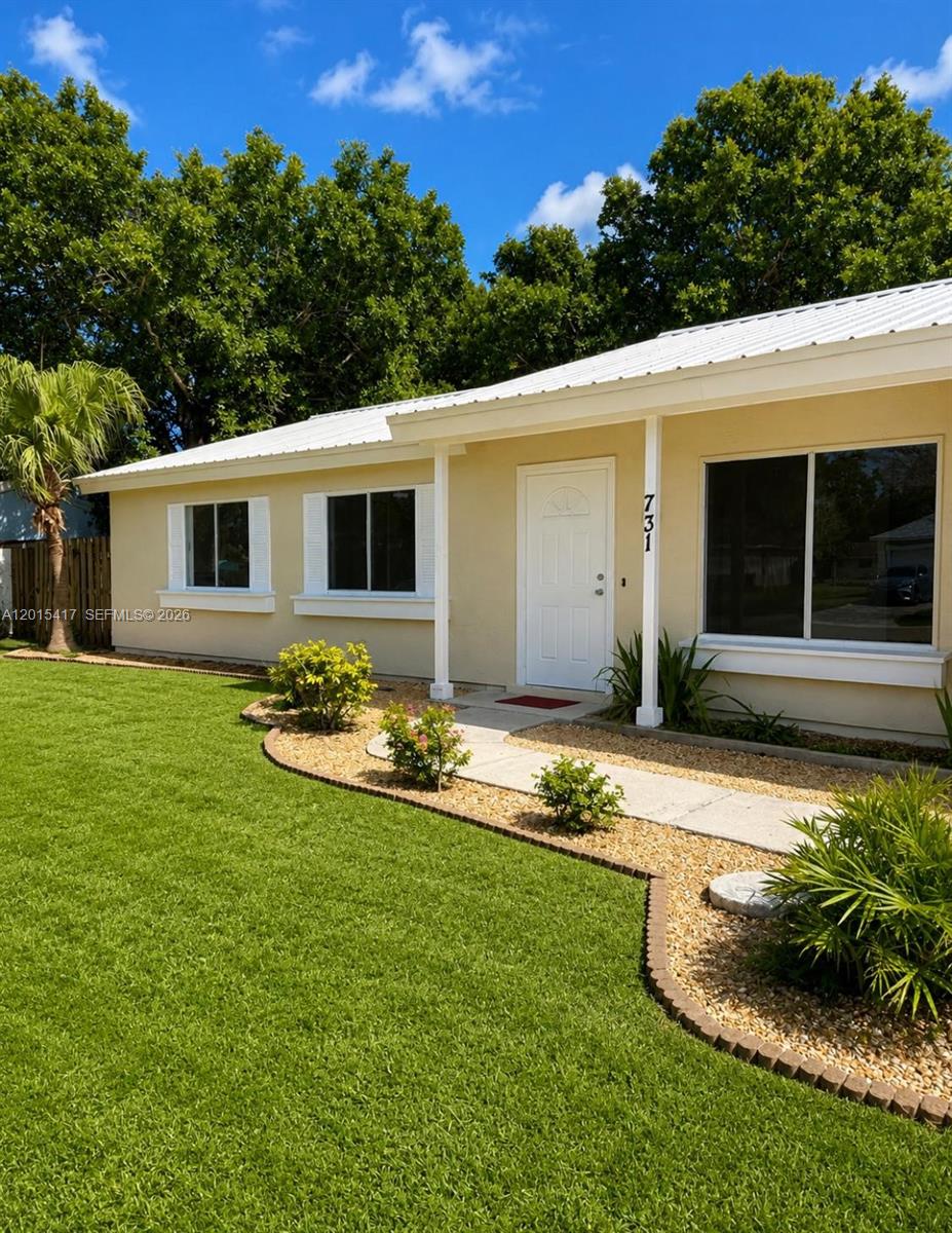 A single-story house with a beige exterior, white trim, and a landscaped front yard — 731 SW 24th St, Vero Beach FL 32962, VERO BEACH, FL