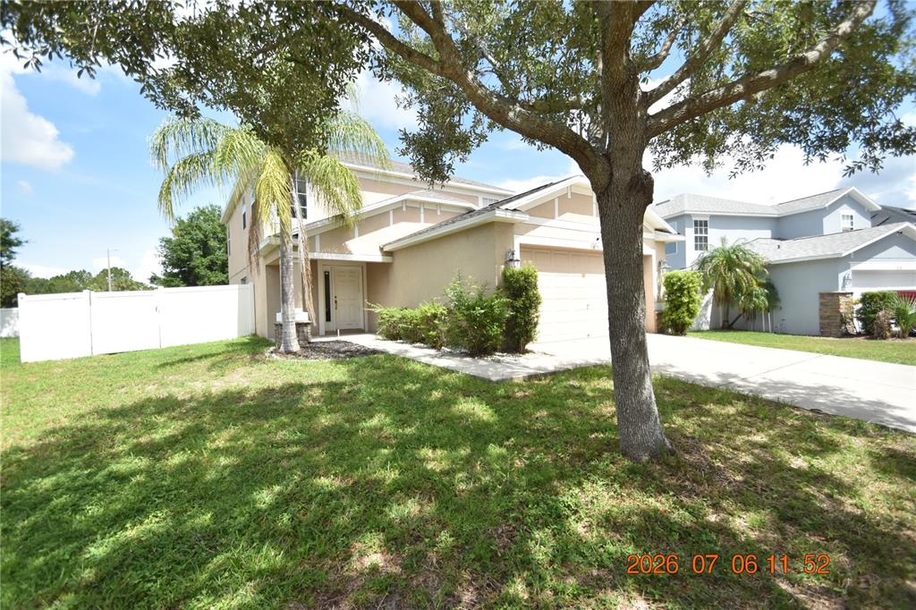 A two-story tan house with a white front door, a garage, and a front lawn — 13556 FLADGATE MARK DRIVE, RIVERVIEW, FL