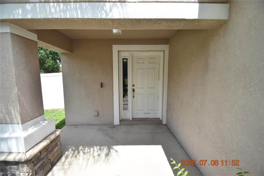 A covered concrete porch leads to a white front door with a side window panel — 13556 FLADGATE MARK DRIVE, RIVERVIEW, FL