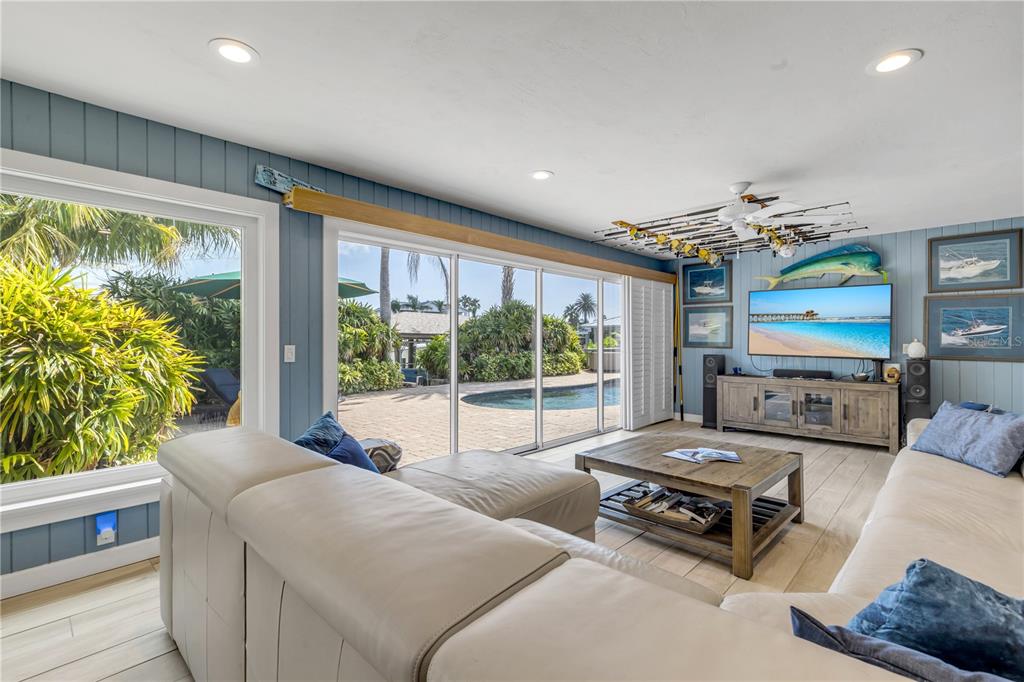 A living room features a white sectional sofa, a wooden coffee table, and sliding glass doors — 109 VIA BENEVENTO, NEW SMYRNA BEACH, FL