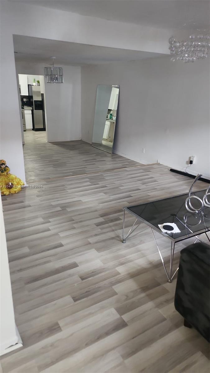An interior view shows a living area with light wood-look flooring and a glass coffee table — 15115 NE 6th Ave # 32, Miami FL 33162, MIAMI, FL