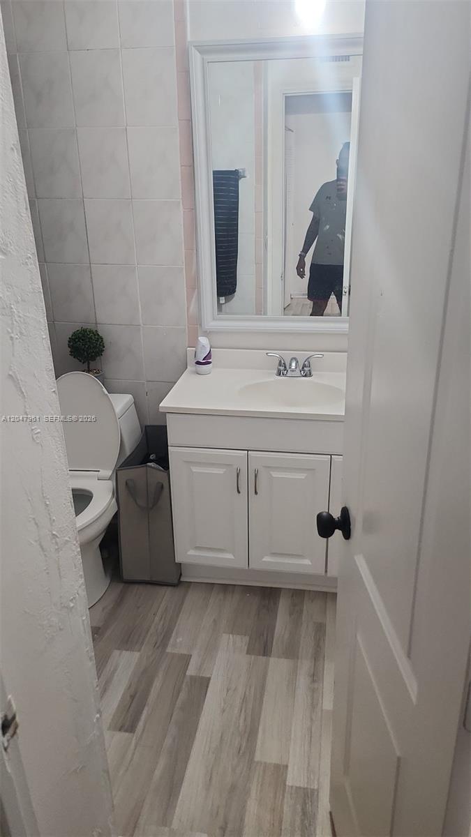 A small bathroom features a white vanity, a toilet, and light wood-look flooring — 15115 NE 6th Ave # 32, Miami FL 33162, MIAMI, FL