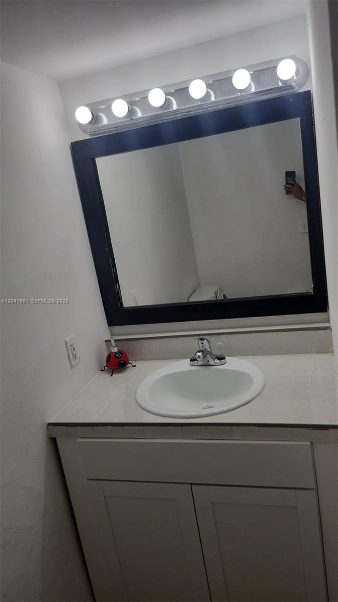 A bathroom features a white vanity, a sink, a dark-framed mirror, and a light fixture — 15115 NE 6th Ave # 32, Miami FL 33162, MIAMI, FL