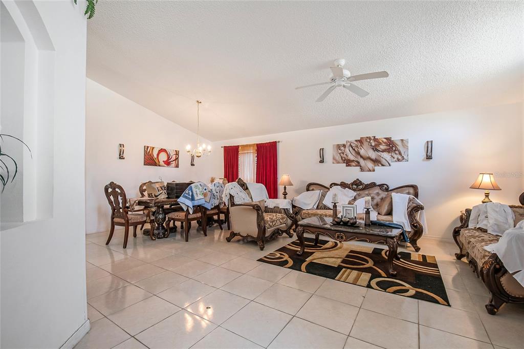 A living and dining area features tile flooring, ornate furniture, and a ceiling fan — 1105 SEASONS BOULEVARD, KISSIMMEE, FL