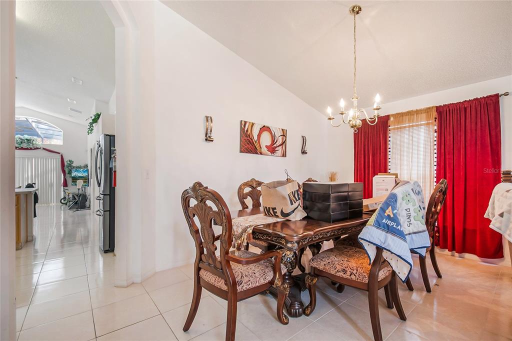 A dining room features a dark wood table, ornate chairs, and red curtains — 1105 SEASONS BOULEVARD, KISSIMMEE, FL
