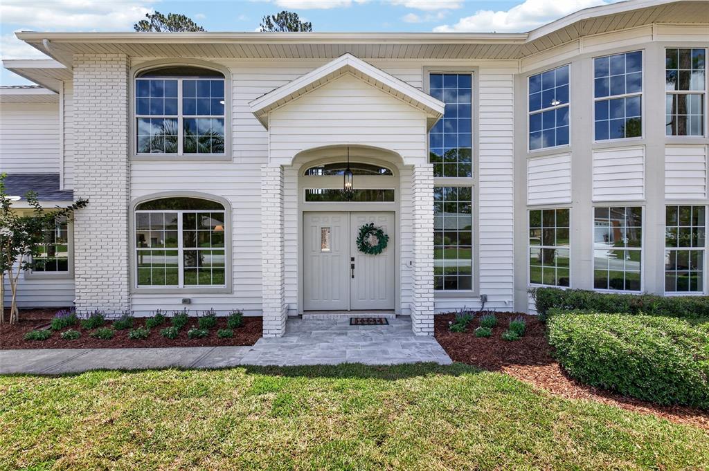 A two-story white house with a brick entryway, double front doors, and large grid windows — 13 ELLSWORTH DRIVE, PALM COAST, FL