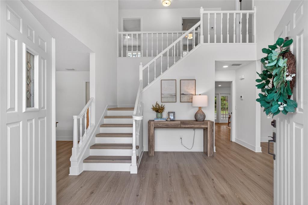 A wooden console table sits in a foyer with a staircase and two framed prints — 13 ELLSWORTH DRIVE, PALM COAST, FL