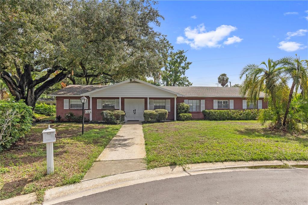 A single-story brick house with a white front door and a concrete walkway — 6401 WINGFOOT CIRCLE, TAMPA, FL