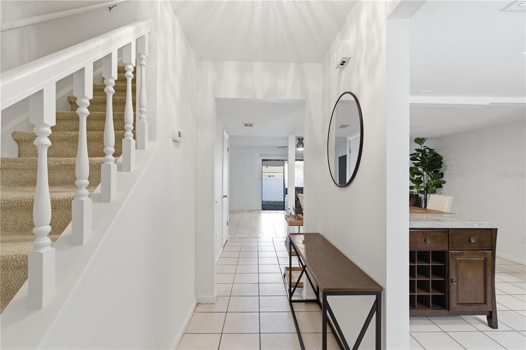 A bright entryway features a carpeted staircase, tiled flooring, a console table, and a mirror — 14804 WINDING CREEK COURT, TAMPA, FL