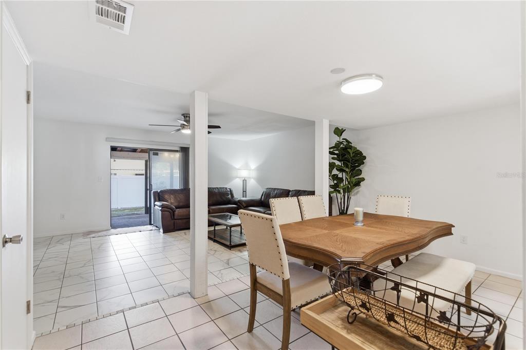 A dining area with a wooden table and chairs opens into a tiled living room — 14804 WINDING CREEK COURT, TAMPA, FL
