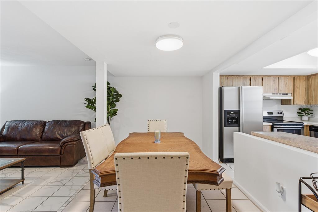 A dining area with a wooden table and upholstered chairs sits between a living room and kitchen — 14804 WINDING CREEK COURT, TAMPA, FL