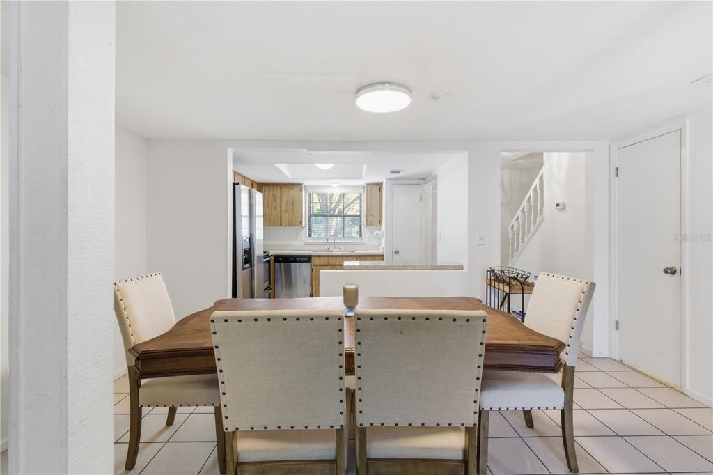 A dining area with a wooden table and upholstered chairs sits before an open kitchen — 14804 WINDING CREEK COURT, TAMPA, FL