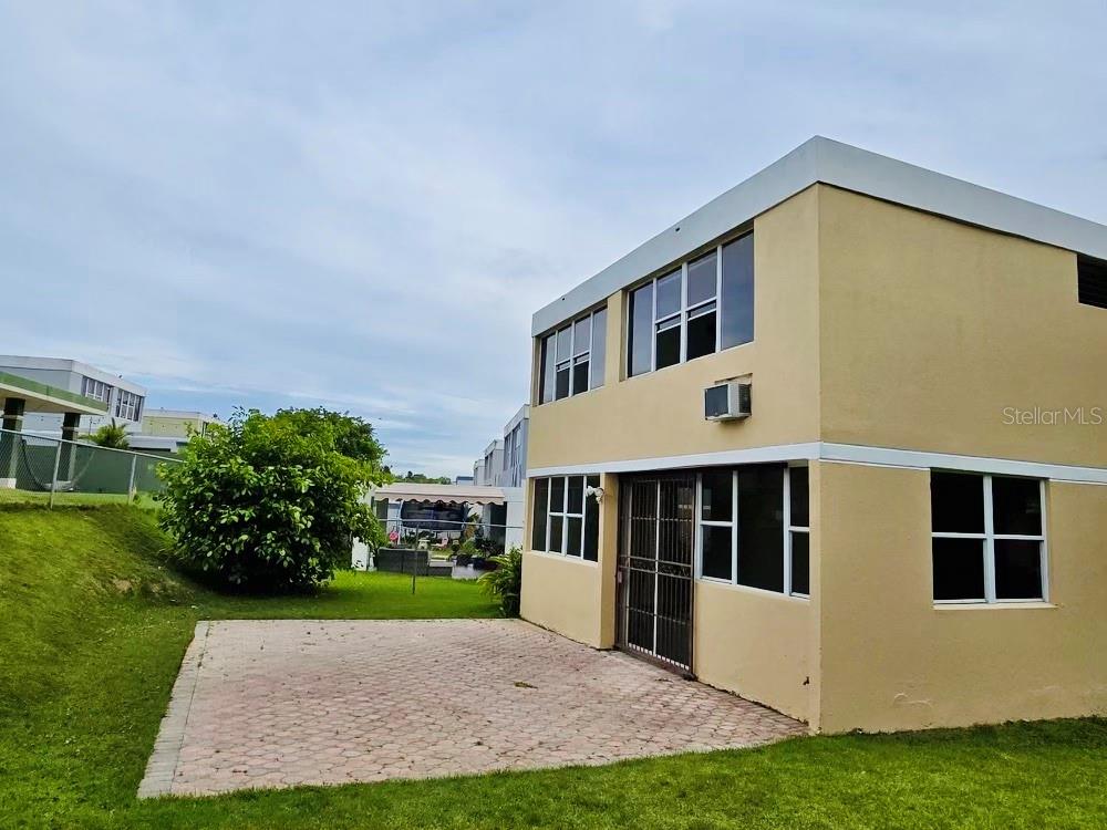 A two-story tan building with a paved patio area and a grassy yard — D-1 FLAMINGO STREET, DORADO, PR