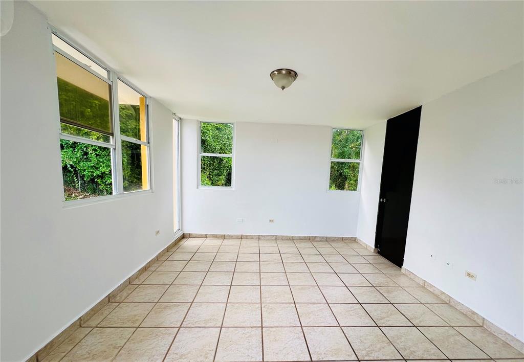 An empty room with white walls, tiled floors, a ceiling light, and several windows — D-1 FLAMINGO STREET, DORADO, PR