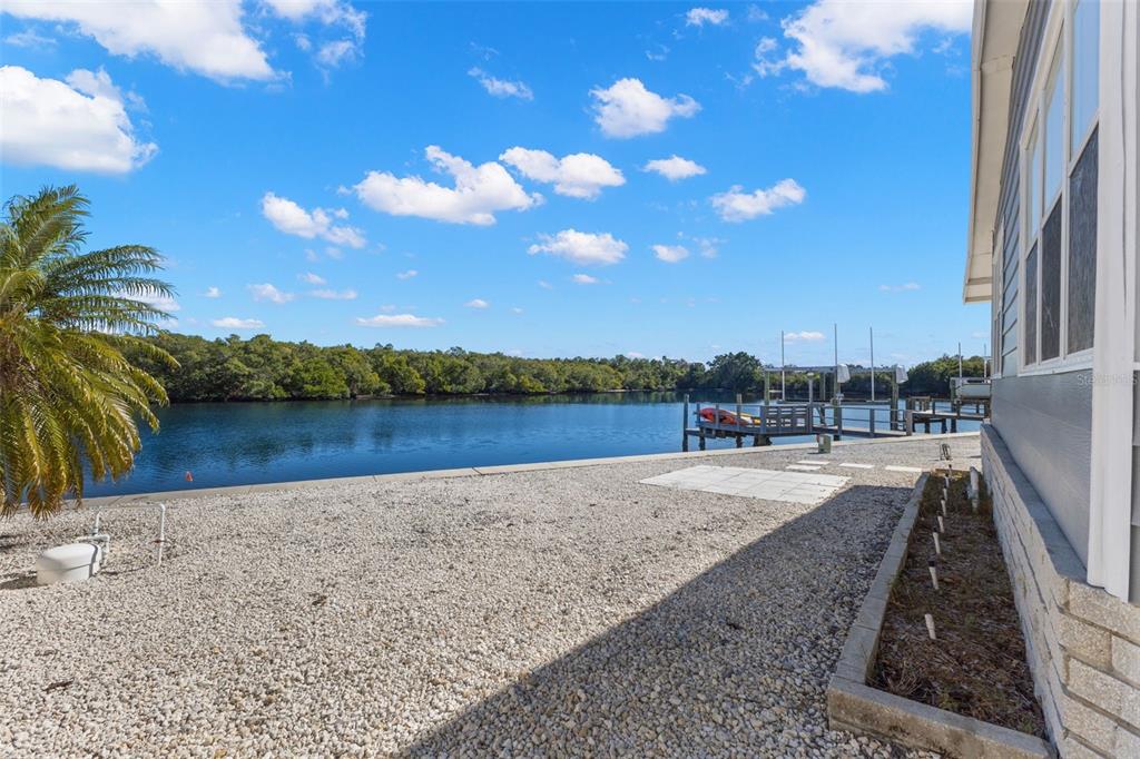 A gravel yard sits beside a house, overlooking a canal with a private boat dock — 7113 MOUNT PINEY ROAD NE UNIT 719, ST PETERSBURG, FL