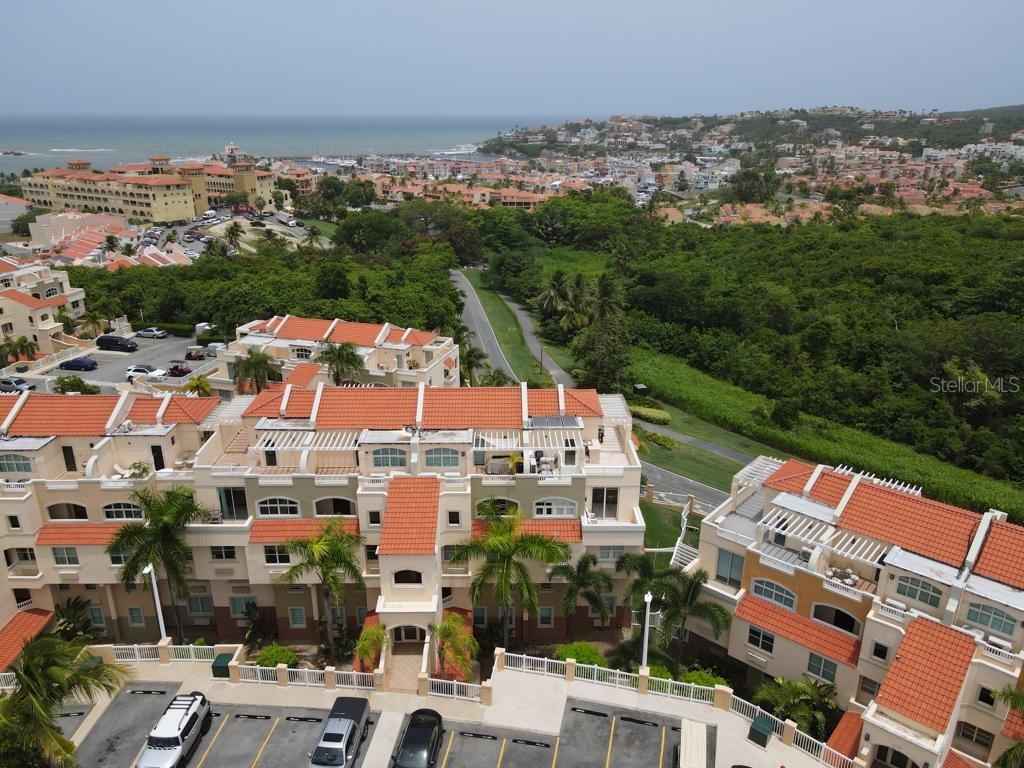 An aerial view shows multi-story residential buildings with orange tiled roofs and a parking lot — Palms Inn Drive PALMANOVA VILLAGE UNIT 2-304, HUMACAO, PR
