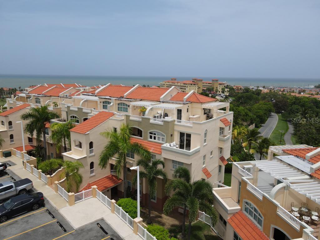 An aerial view of a multi-story residential building with orange tile roofs and palm trees — Palms Inn Drive PALMANOVA VILLAGE UNIT 2-304, HUMACAO, PR