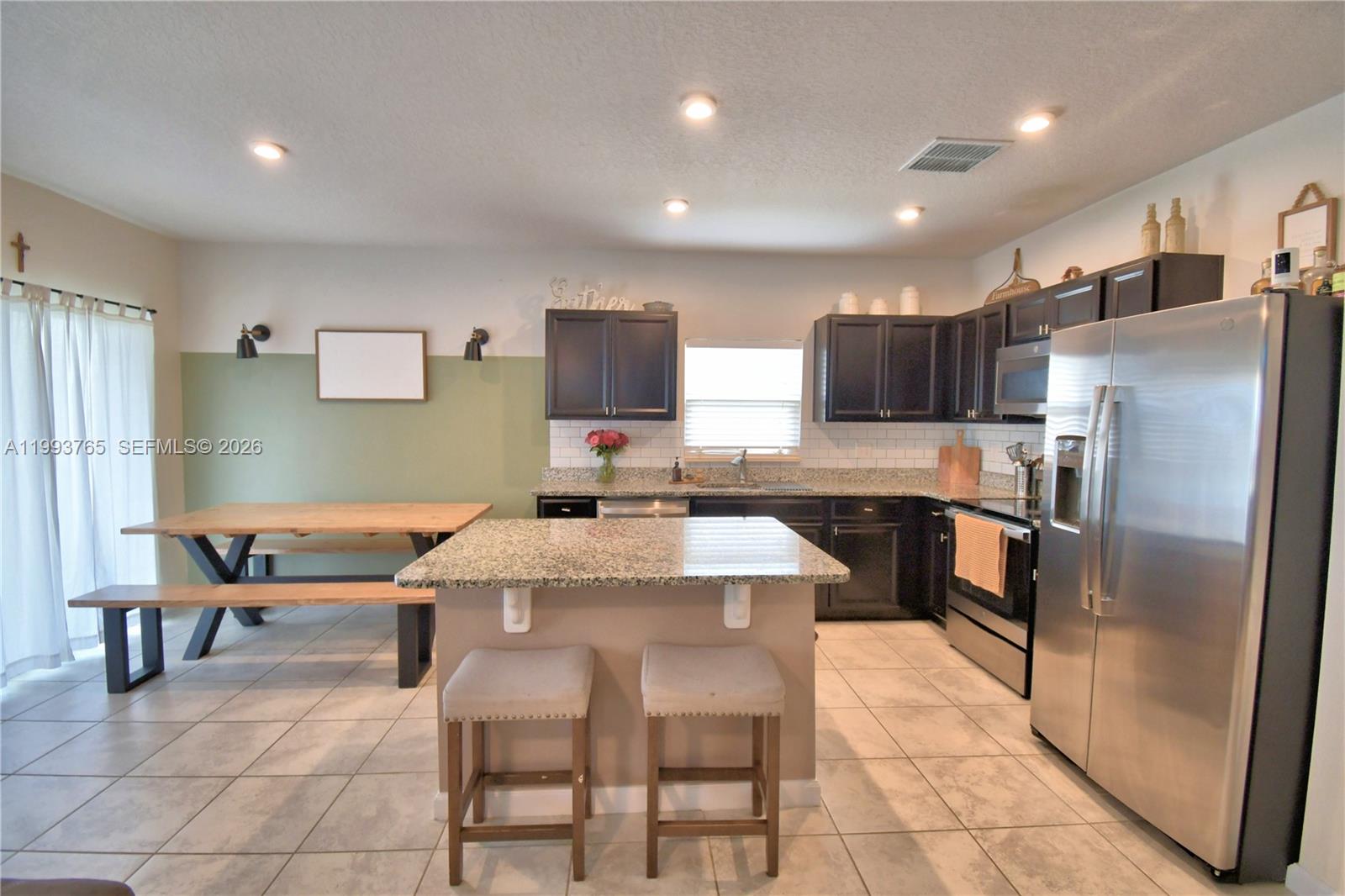 A kitchen features dark cabinets, granite countertops, a central island, and an adjacent dining area — 542 Eagle Landing Blvd., Winter Haven FL 33880, WINTER HAVEN, FL