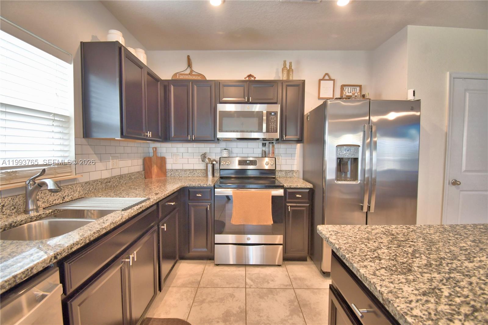 A kitchen features dark cabinets, granite countertops, stainless steel appliances, and a white subway tile backsplash — 542 Eagle Landing Blvd., Winter Haven FL 33880, WINTER HAVEN, FL