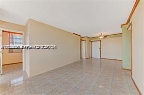An interior view shows a living area with light-colored tile flooring and beige walls — 2025 NE 164th St # 904, North Miami Beach FL 33162, NORTH MIAMI BEACH, FL