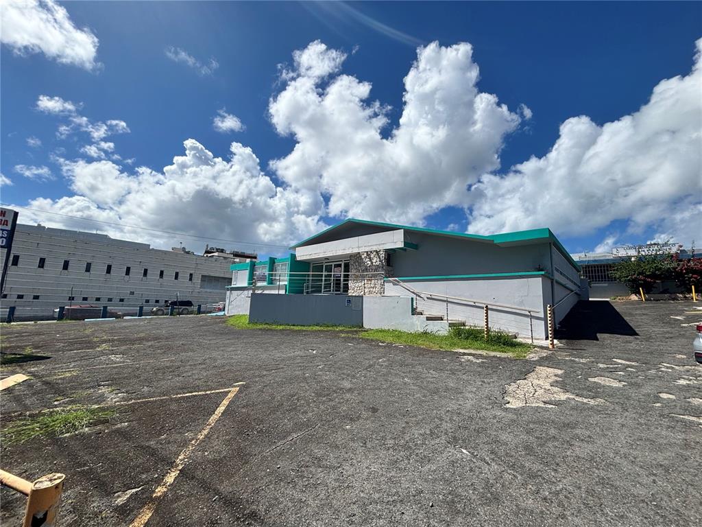 A gray commercial building with teal trim and a paved parking lot under a cloudy sky — 47 AVE JOSE DE DIEGO UNIT 32, SAN JUAN, PR