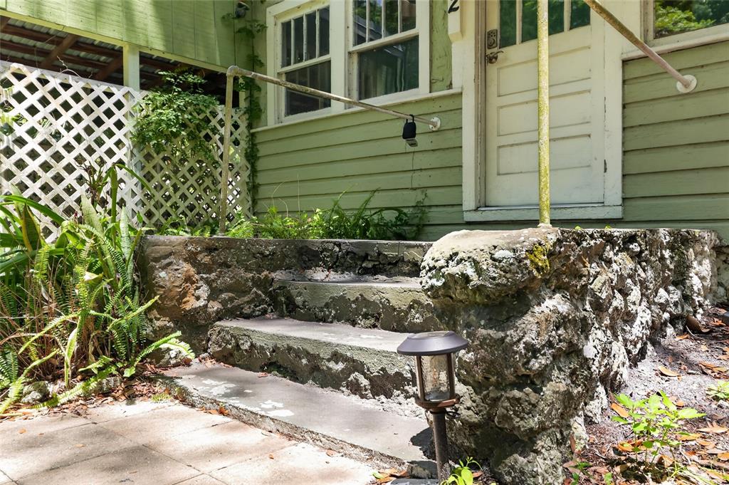 A set of weathered concrete steps leads to the front door of a green house — 2 ALLEY A, YANKEETOWN, FL