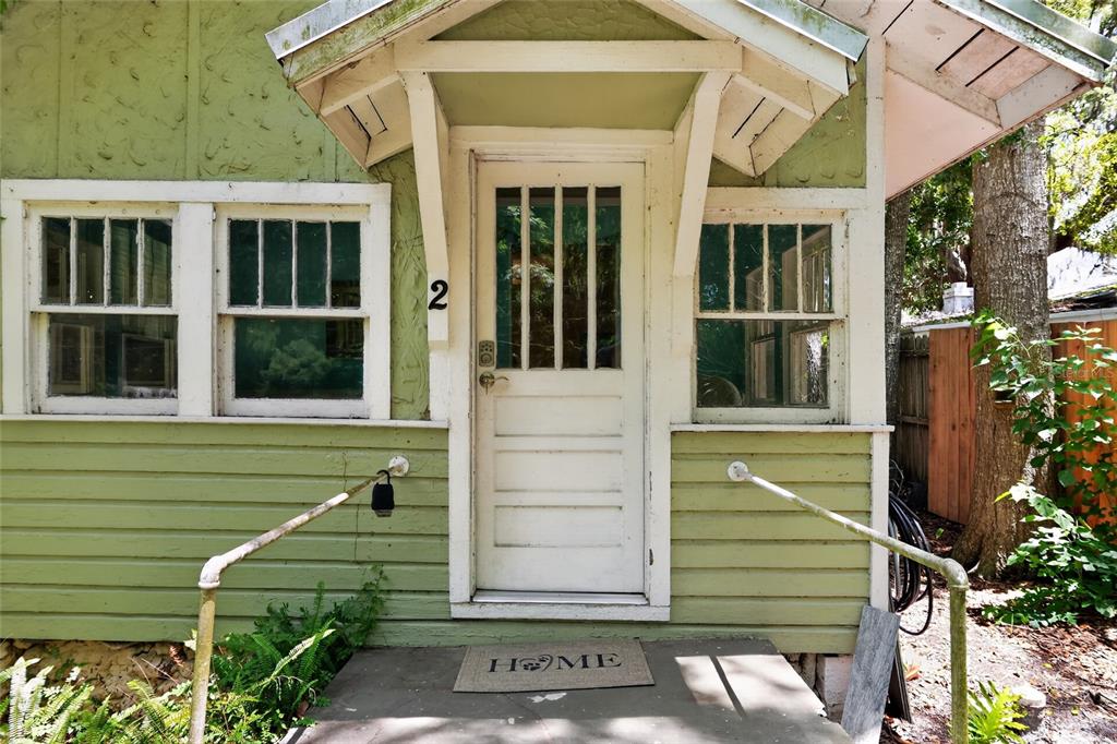 A green house exterior features a white front door with a small porch and railings — 2 ALLEY A, YANKEETOWN, FL