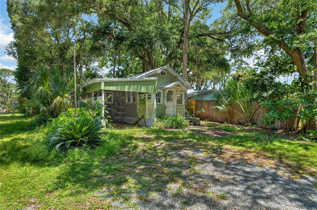 A small, light green cottage with a covered porch sits on a gravel lot — 2 ALLEY A, YANKEETOWN, FL