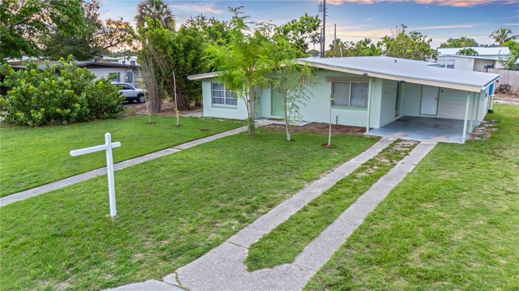 A light green single-story house with a carport and a front yard with a sign — 180 PALMETTO CIRCLE NE, PORT CHARLOTTE, FL