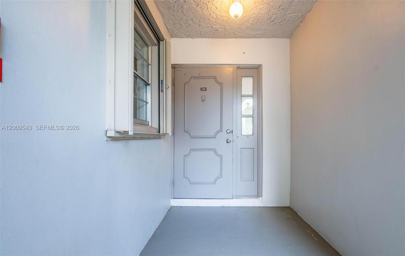 A gray front door with a side window is located in a covered entryway — 9340 Lagoon Pl # 110, Davie FL 33324, DAVIE, FL