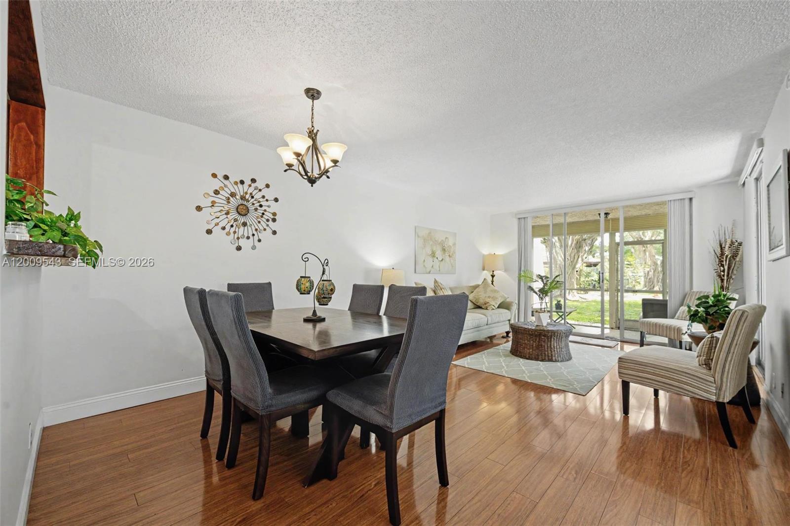 A dining area with a wooden table and chairs flows into a living room with sliding doors — 9340 Lagoon Pl # 110, Davie FL 33324, DAVIE, FL