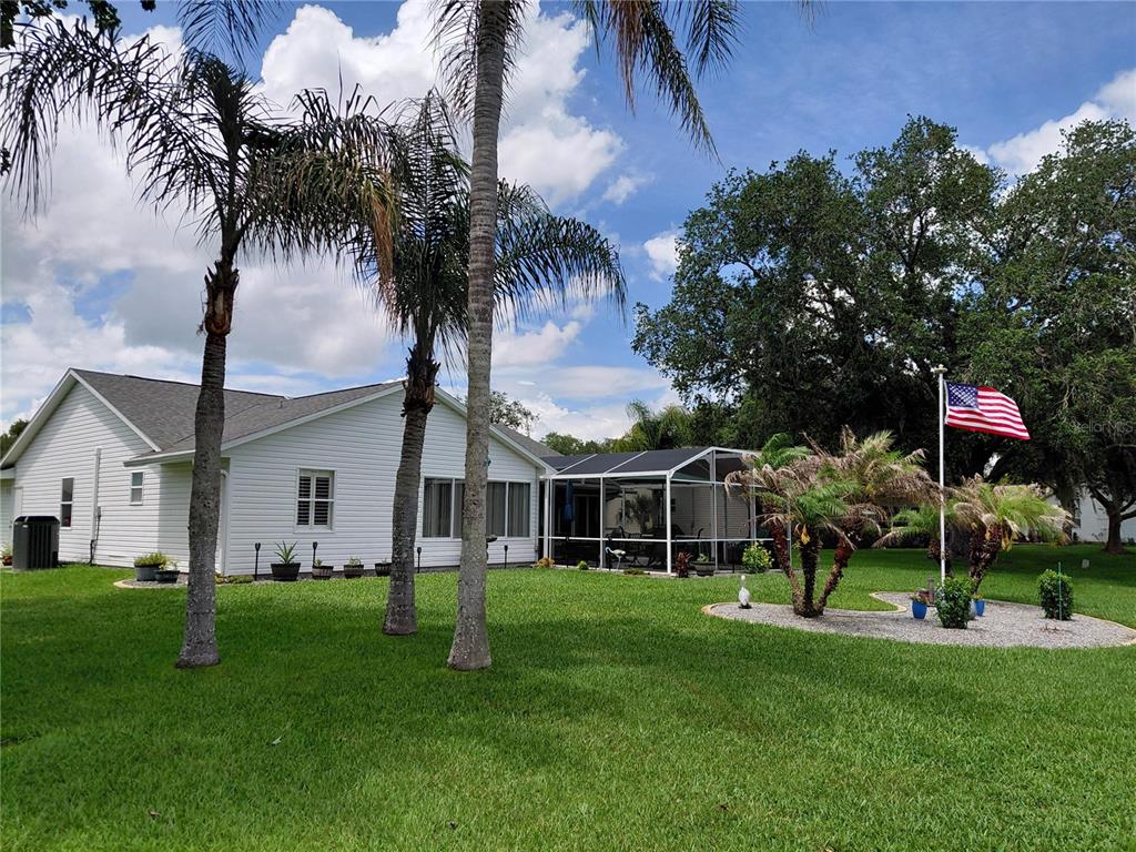 A white house with a screened-in patio and palm trees in a grassy yard — 26010 NEWCOMBE CIRCLE, LEESBURG, FL