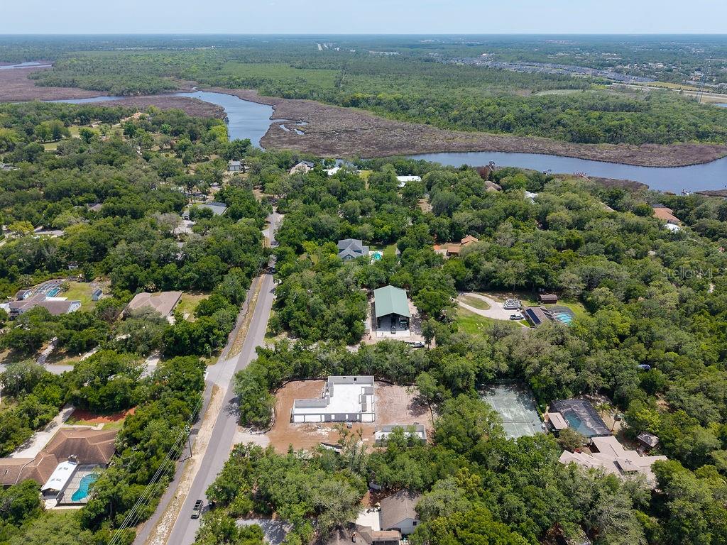 An aerial view shows a wooded residential area with a river and a house under construction — 6030 HENSEL ROAD, PORT ORANGE, FL