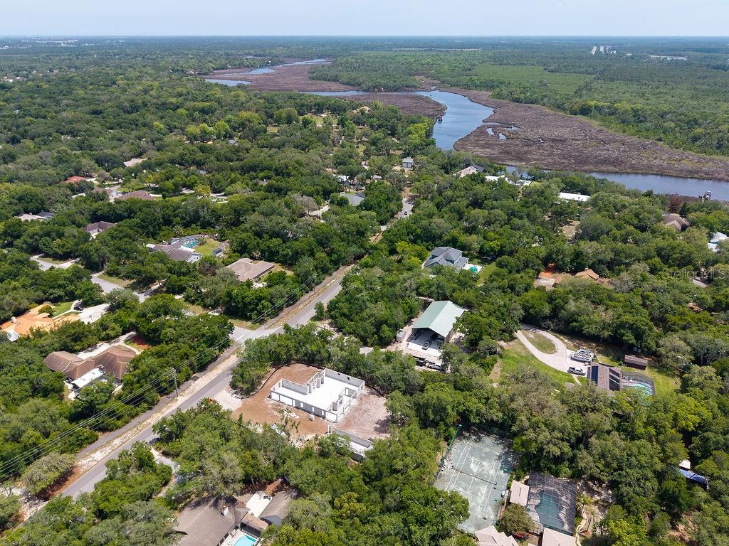An aerial view shows a wooded residential area with a river and a house under construction — 6030 HENSEL ROAD, PORT ORANGE, FL