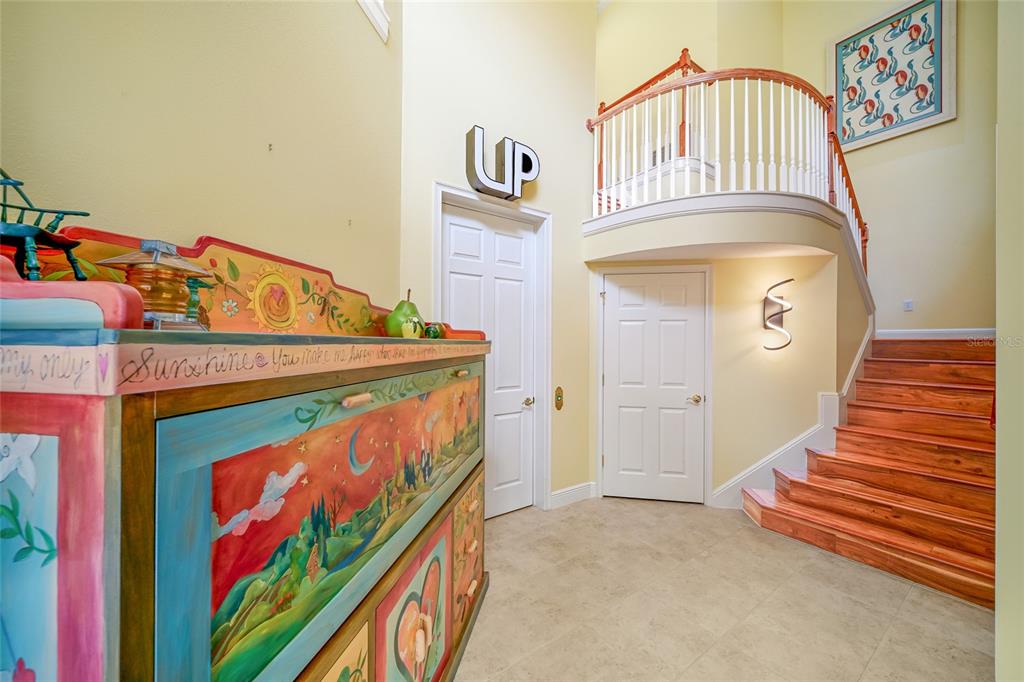 An entryway features a painted wooden chest, a staircase with wood treads, and a balcony — 6435 MOORINGS POINT CIRCLE UNIT 201, LAKEWOOD RANCH, FL