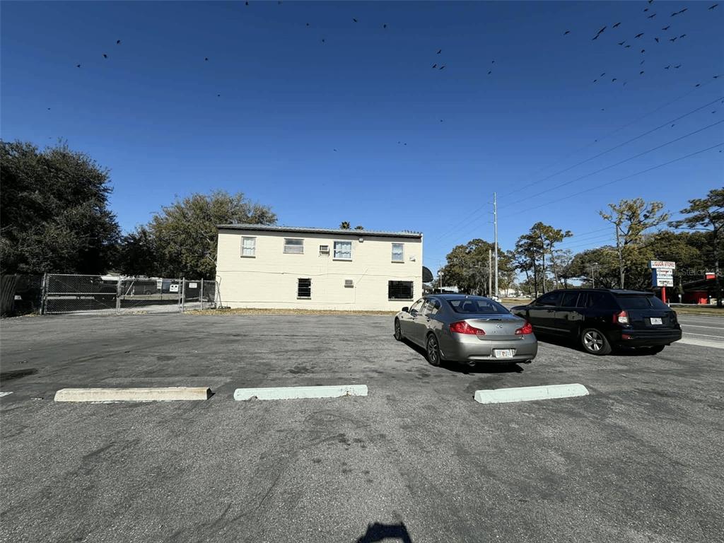 A two-story beige building stands behind a paved parking lot with two parked cars — 5508 EDGEWATER DRIVE, ORLANDO, FL