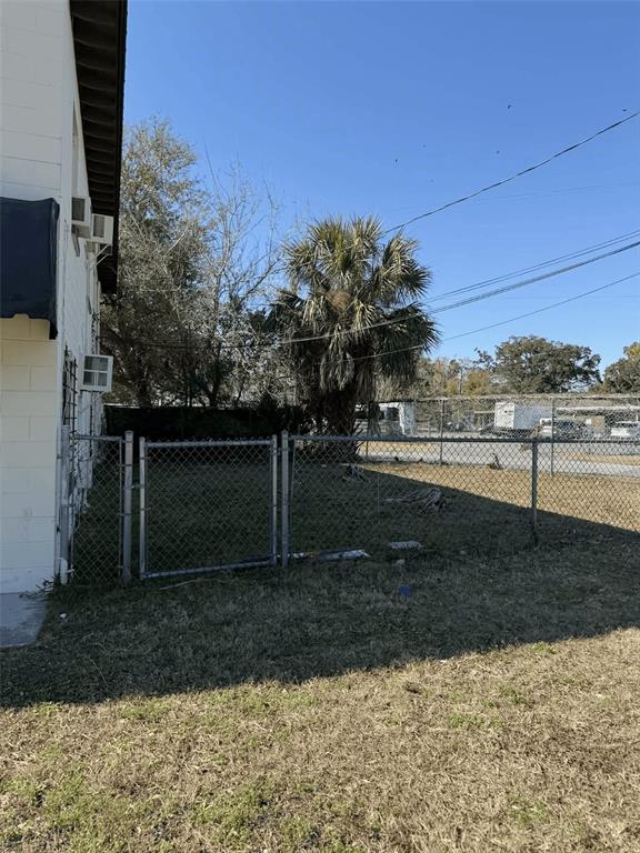 A chain-link fence encloses a grassy yard next to the side of a building — 5508 EDGEWATER DRIVE, ORLANDO, FL