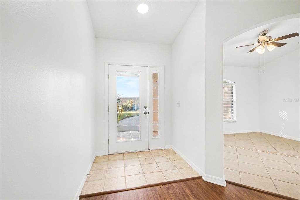 A bright entryway features a white front door with a sidelight and tiled flooring — 10423 LAKE HASSON CIRCLE, CLERMONT, FL
