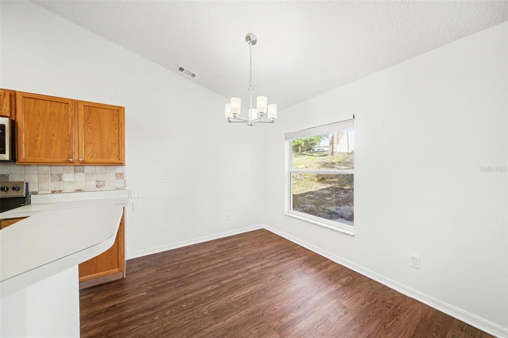 A dining area with wood-look flooring, white walls, a chandelier, and a window — 10423 LAKE HASSON CIRCLE, CLERMONT, FL