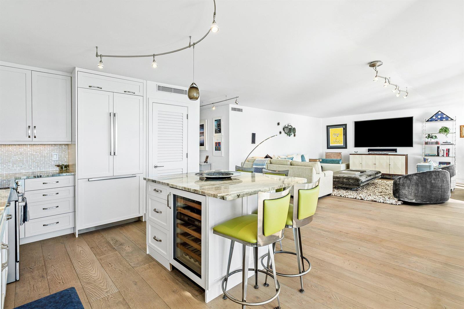A bright, open-concept kitchen and living area featuring white cabinetry, a stone island, and hardwood floors — 2800 S Ocean Boulevard # c, Boca Raton FL 33432, BOCA RATON, FL