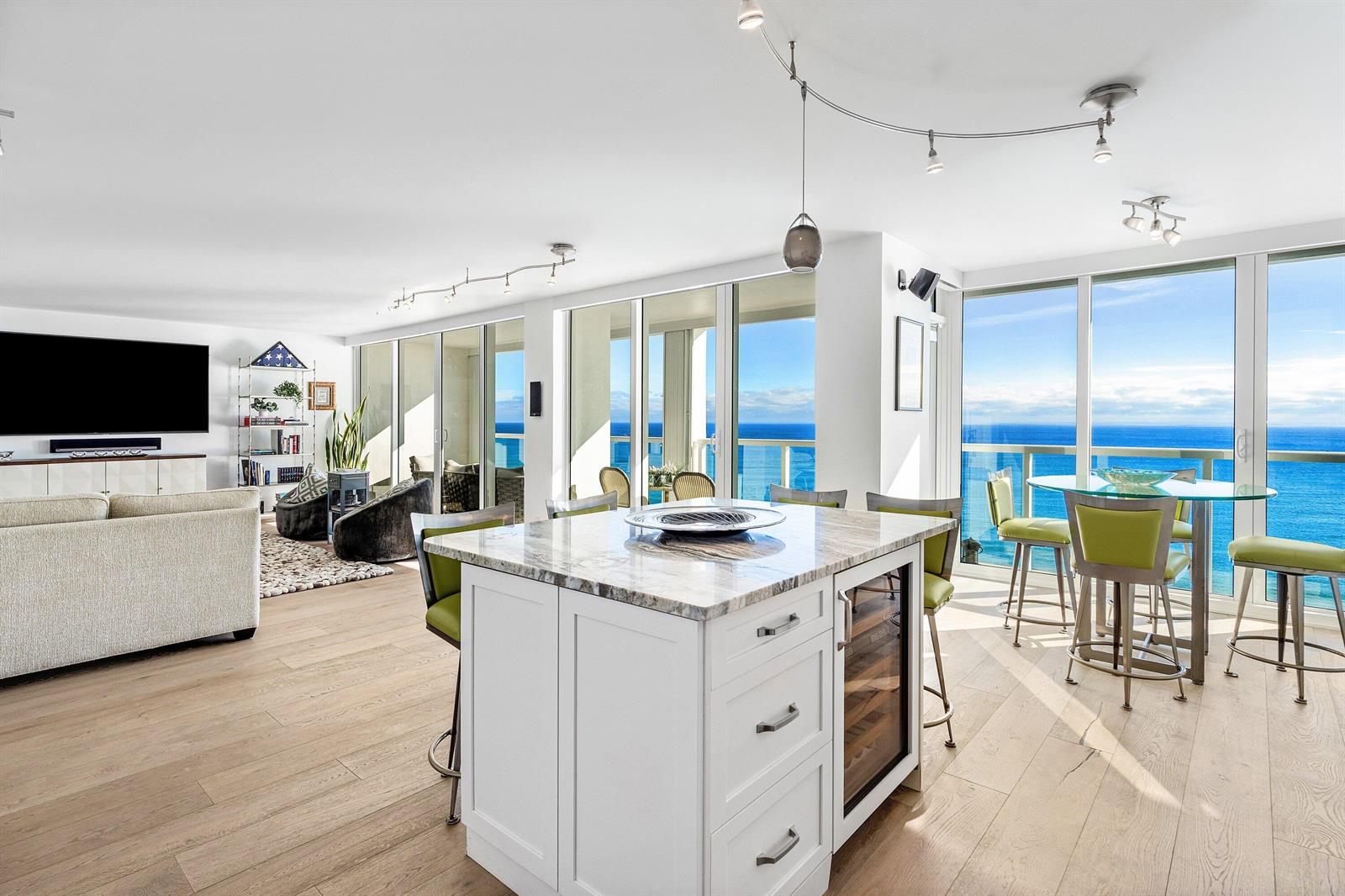 A modern kitchen island and dining area overlook the ocean through floor-to-ceiling windows — 2800 S Ocean Boulevard # c, Boca Raton FL 33432, BOCA RATON, FL
