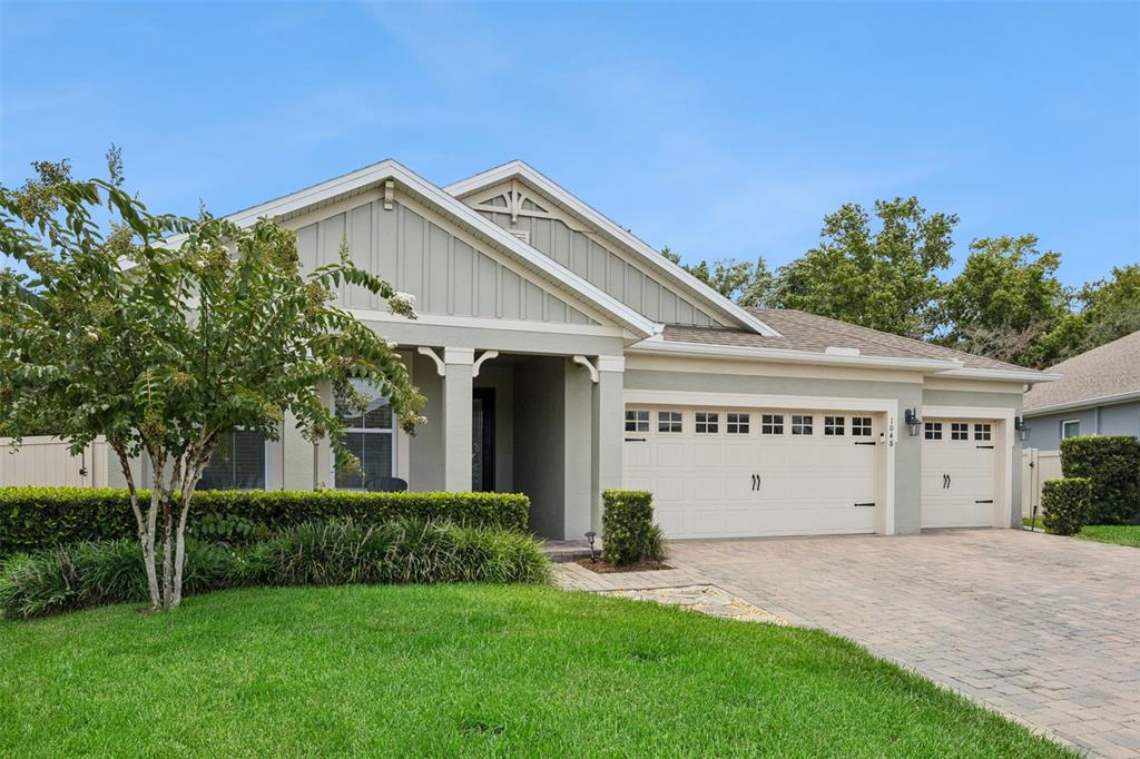 A single-story house with a light green exterior, a paved driveway, and a two-car garage — 1048 WOOD DALE CIRCLE, OVIEDO, FL