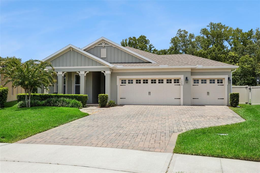 A single-story house with a gray exterior, a paver driveway, and a three-car garage — 1048 WOOD DALE CIRCLE, OVIEDO, FL